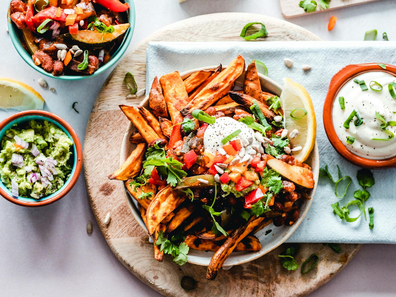 A vibrant platter of savory sweet potato fries with fresh toppings, perfect for a tasty snack.